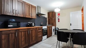 Une cuisine compacte avec des meubles en bois, un four à micro-ondes, un grille-pain et un lave-linge.