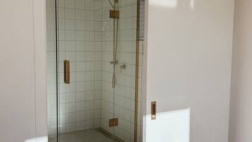 A modern bathroom with a glass shower enclosure, white tiled walls, and a black sliding door.