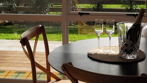 A dining area with a table, chairs, and a view of a green landscape through large windows. - Willow View Cottage with beautiful country views - Near Waitomo (Otorohanga)