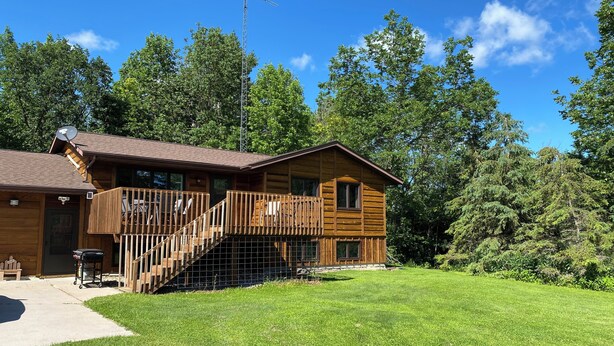 Une cabane en bois dotée d’un balcon, d’un escalier et d’une antenne parabolique.