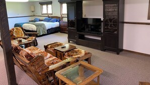 Une chambre d’hôtel comprenant un lit, deux chaises, une table, un téléviseur et une armoire.
