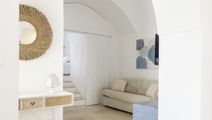 Ein modernes Wohnzimmer mit einem weißen Sofa, einem dekorativen Spiegel und einer Treppe, die in einen anderen Raum führt.