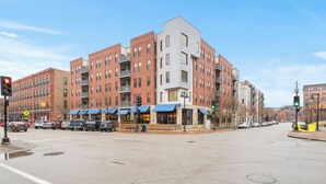 A multi-story building with a mix of brick and modern architectural styles, featuring storefronts with awnings. - Near Wells Fargo, King Bed and Balcony and washer dryer, fitness room, Fireplace (Des Moines)