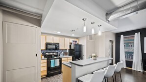 A modern kitchen with a central island, bar stools, and a microwave. - Near Wells Fargo, King Bed and Balcony and washer dryer, fitness room, Fireplace (Des Moines)