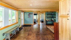 A spacious hallway with wooden floors and walls, leading to a bedroom with a bed and a bathroom. - Bull Moose on Snowmobile, ATV trails, near Sugarloaf, Flagstaff, Hiking, Golfing (Eustis)