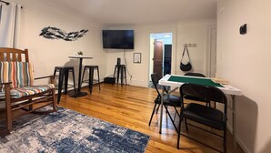 Un salon comprenant une table de billard, un téléviseur et un coin repas avec des chaises.