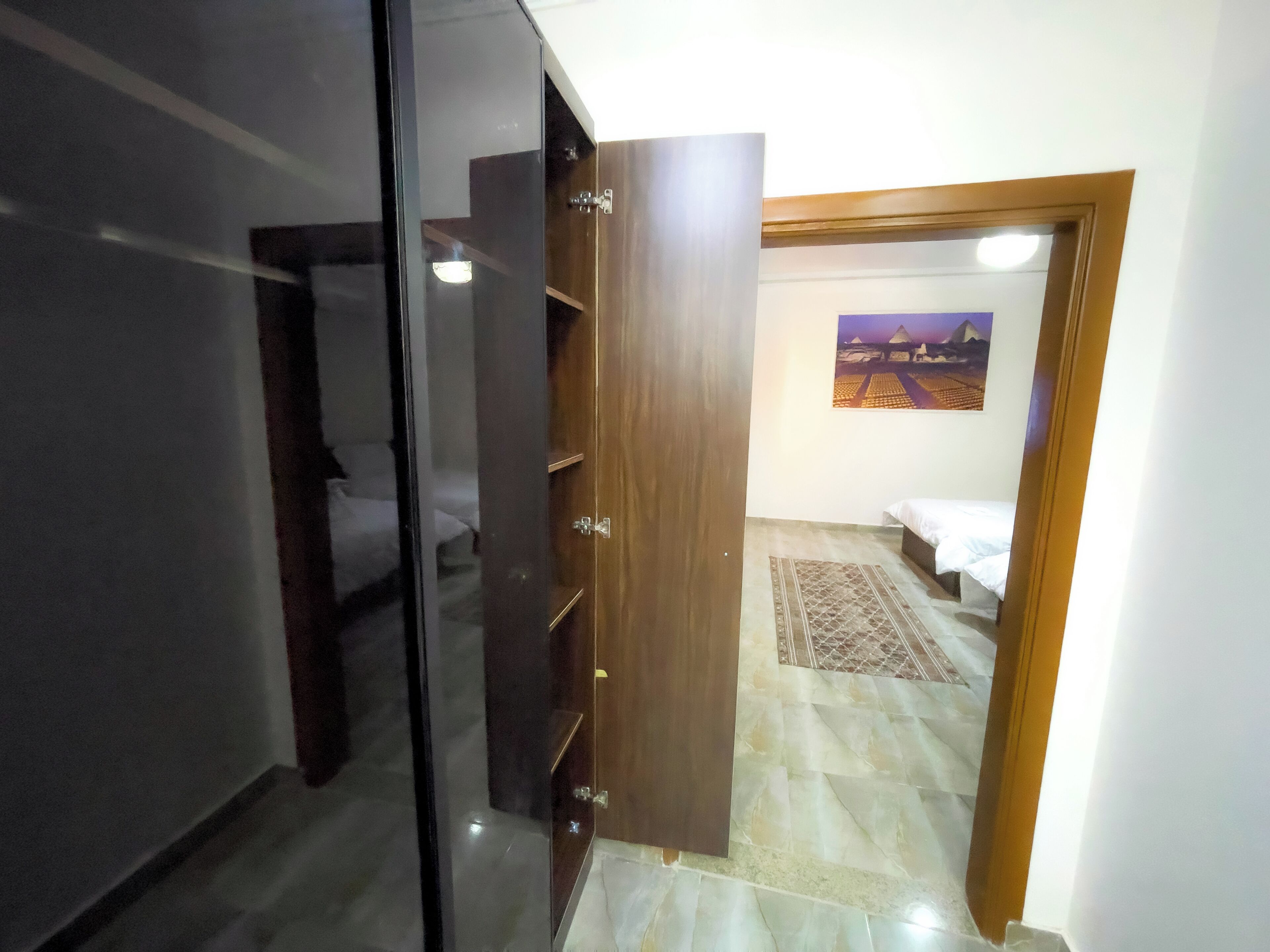Une pièce avec un lit, une armoire en bois et un tableau au mur.