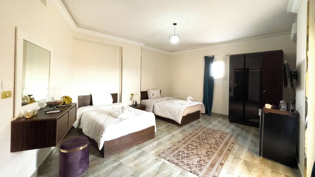 A hotel room with a large bed, a smaller bed, a desk, a wardrobe, and a bathroom. - Sneferu Pyramids Golden Gate (Giza)