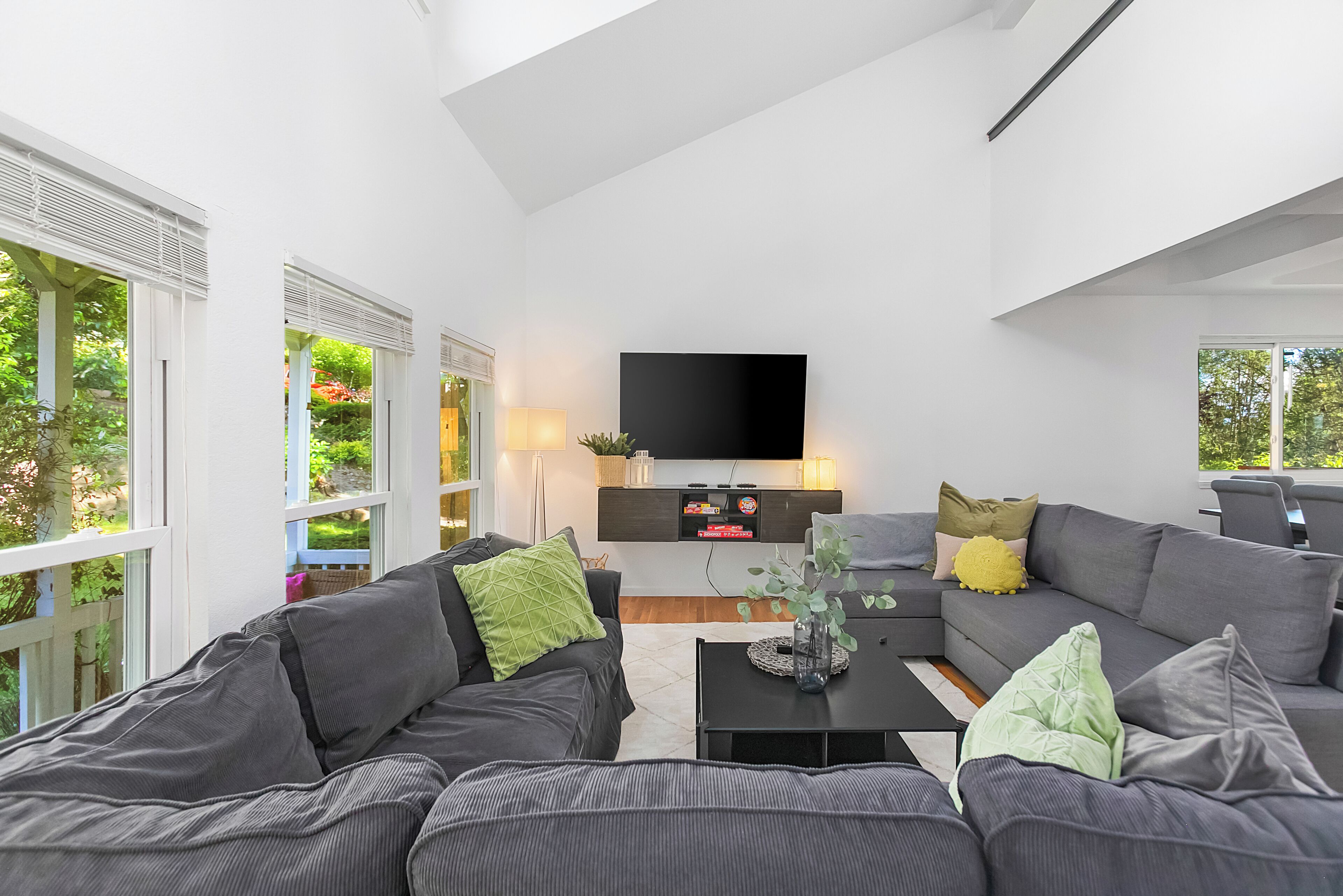 A modern living room with a flat-screen TV, grey sofas, and a coffee table.