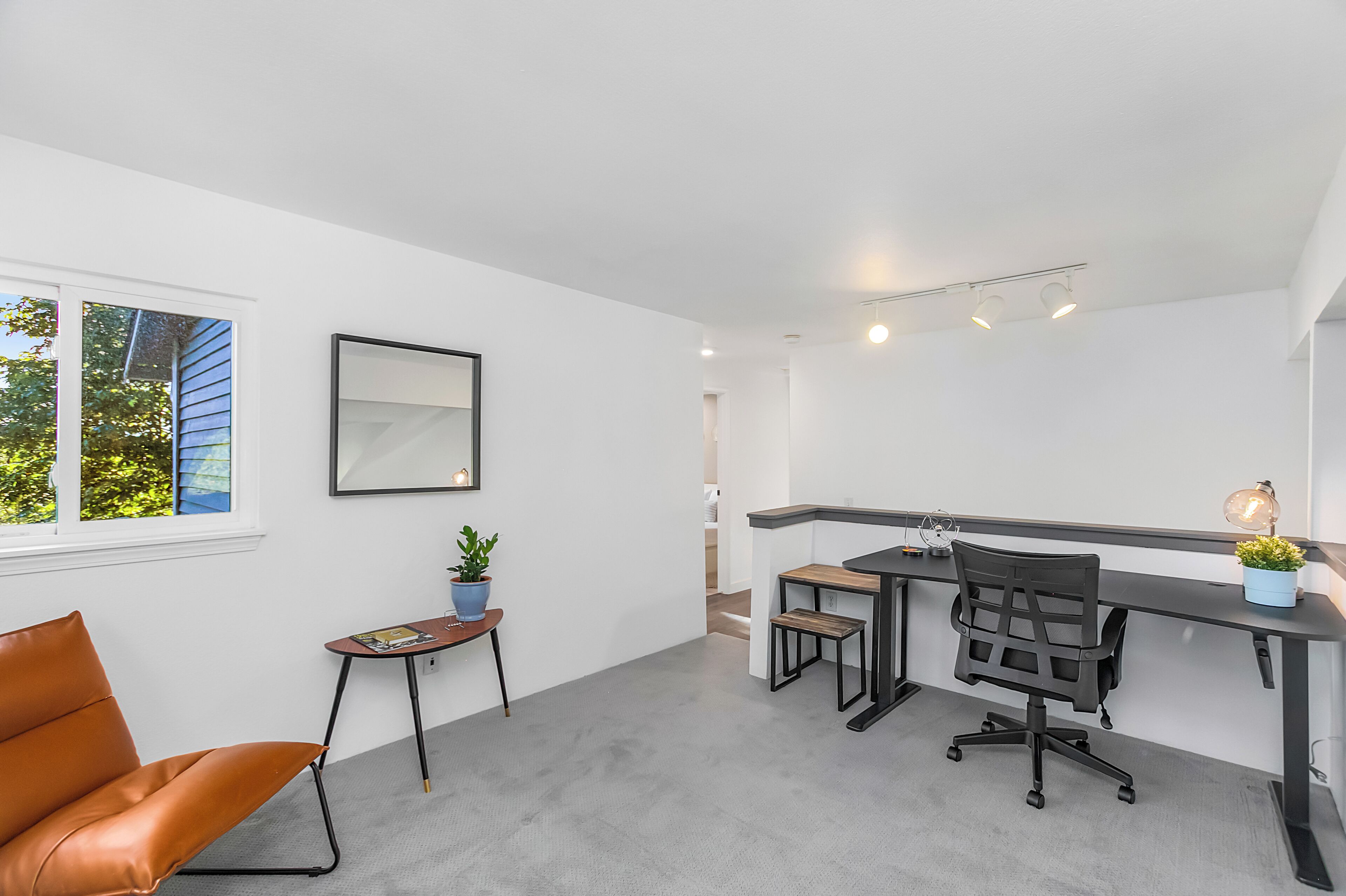 Um espaço de escritório moderno com uma mesa, cadeira e uma pequena mesa com uma planta.