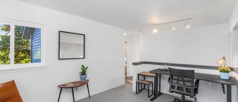 A modern office space with a desk, chair, and a small table with a plant.