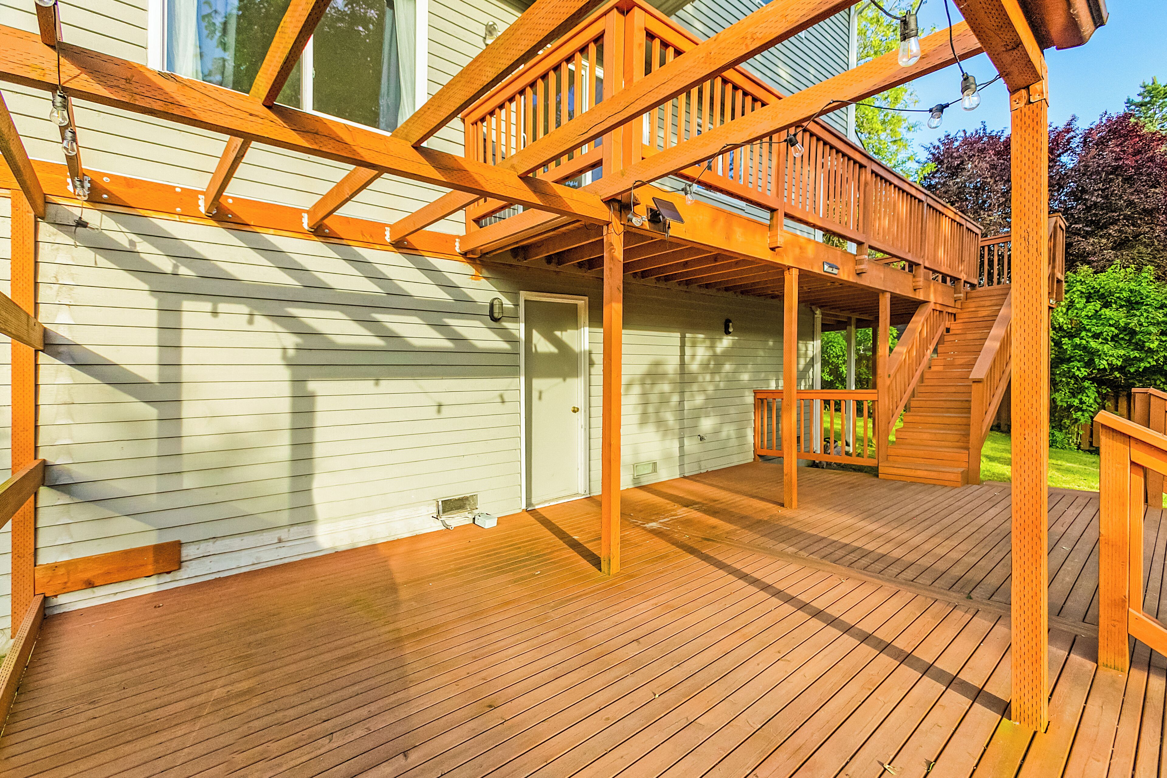A wooden deck with a staircase leading to a covered area.
