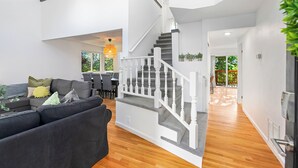 Ein großzügiger Wohnbereich mit moderner Treppe, einem grauen Sofa und einem Essbereich.