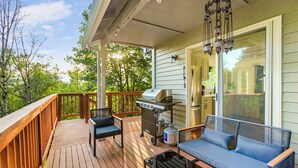 Eine Holzterrasse mit Grill, einer Sitzecke und einem Sessel.