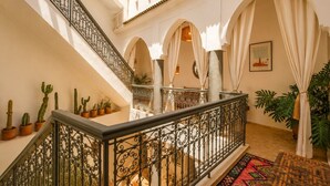 A spacious courtyard with a staircase, arches, potted cacti, and a framed picture on the wall. - Riad Belvi - Breakfast - 10mn Jemaa El Fnaa-Pool (Marrakech)