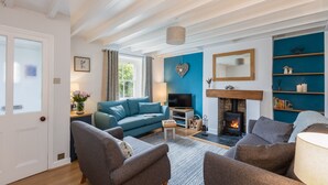 Un salon chaleureux avec un canapé bleu, des fauteuils gris, un téléviseur et une cheminée.