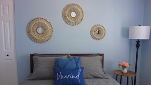 Ein Schlafzimmer mit einem Bett, Kissen, einem Nachttisch mit Lampe und Wanddekoration.