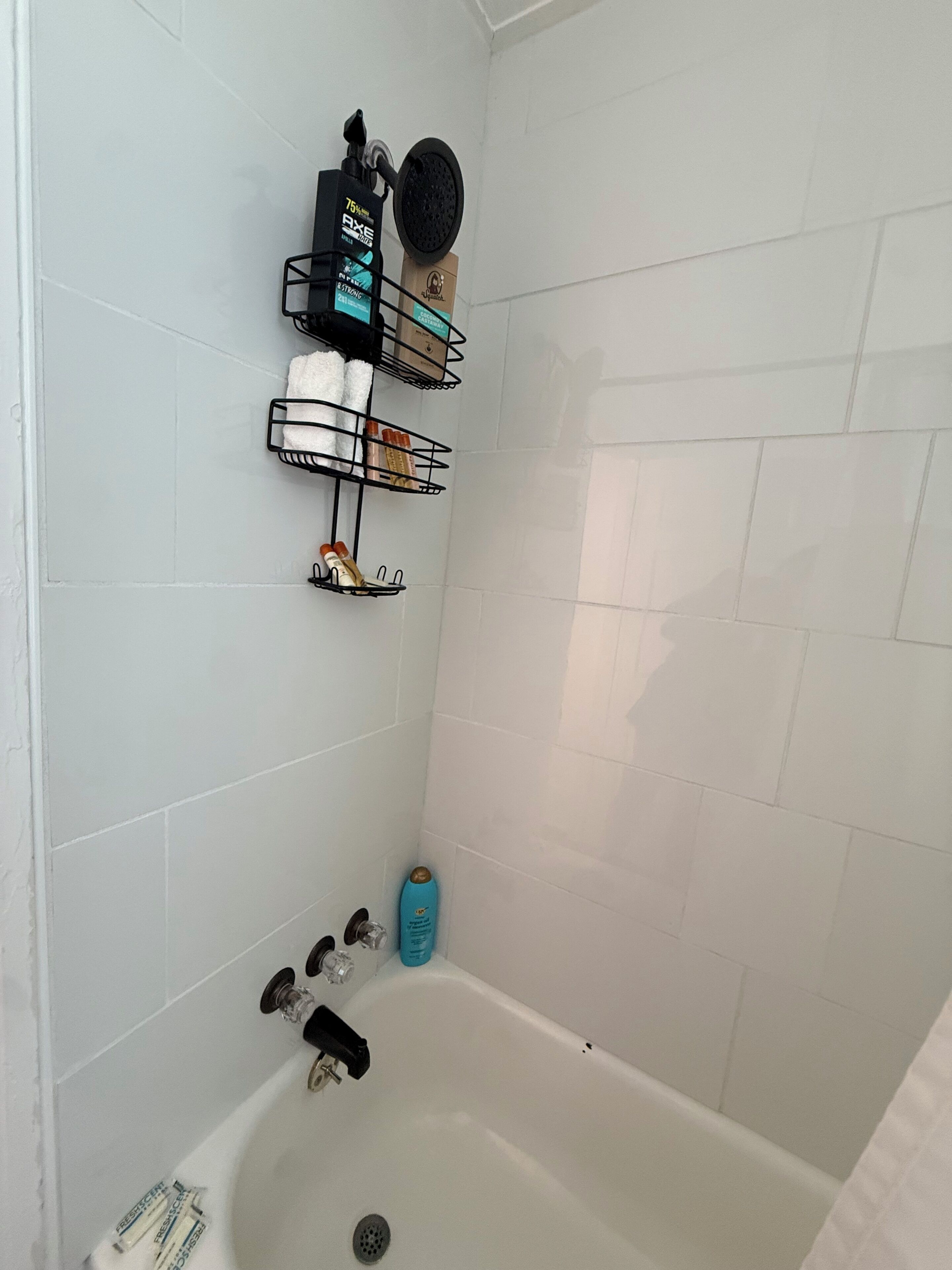 A bathroom with a bathtub, a towel rack, and a shelf with toiletries.