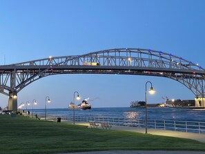 A large steel bridge with multiple lanes, a pedestrian walkway, and a body of water below.
