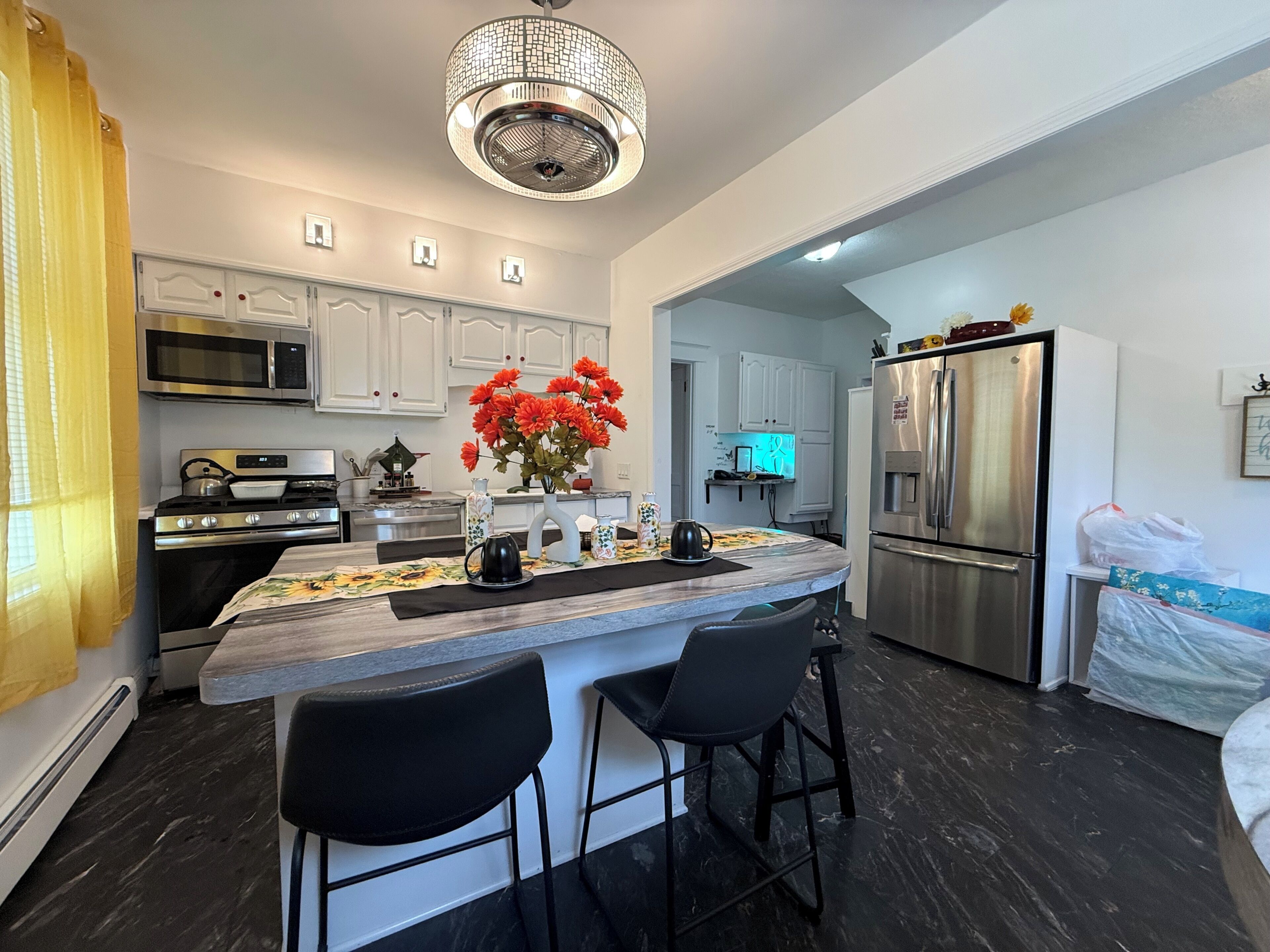 A modern kitchen with a central island, stainless steel appliances, and a chandelier.