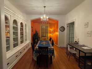 Ein Esszimmer mit einer Pendelleuchte, einem Tisch mit einer blumigen Tischdecke und einer Vitrine mit Glastüren.