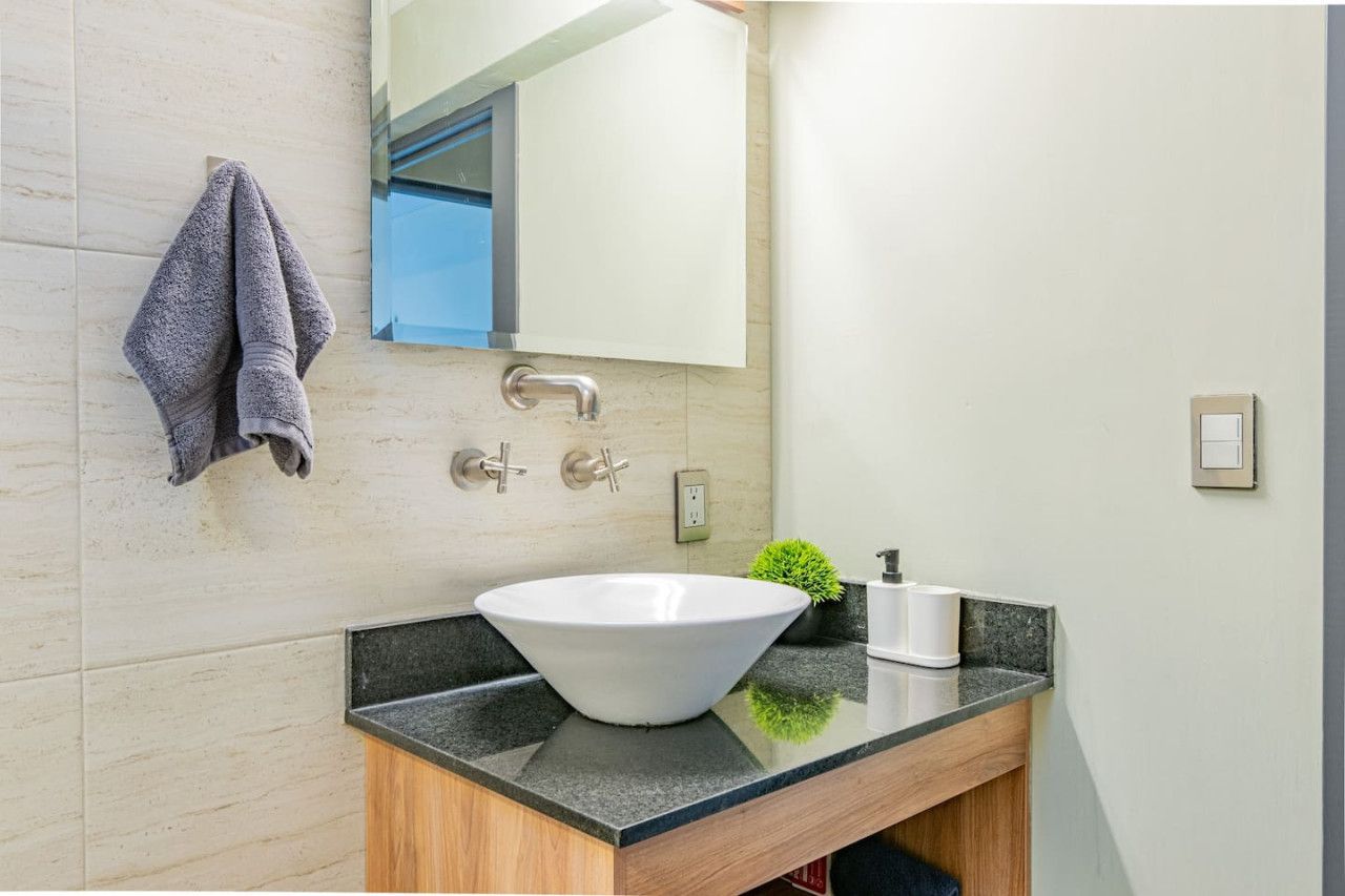 A modern bathroom with a large sink, a towel hanging on the wall, and a mirror above it.