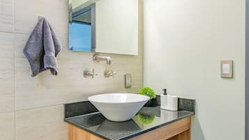 A modern bathroom with a large sink, a towel hanging on the wall, and a mirror above it.