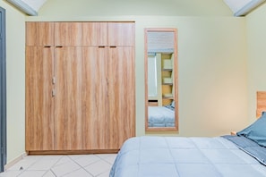 A bedroom with a large wardrobe, a bed with a blue bedspread, and a mirror on the wall. - Hermoso Depa en Centro Historico con Mini split (Durango)