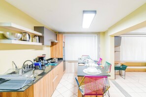 Cocina compacta con comedor, horno empotrado y ventana con persianas.