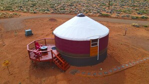 Una yurta con una entrada cubierta y un pequeño porche con una silla y una mesa.