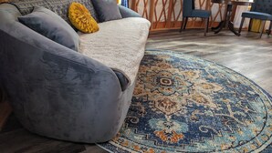 Un salón moderno con un sofá gris, un tapete estampado y una pared de madera decorativa.
