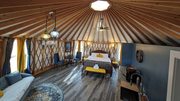 Una habitación amplia con una cama grande, techo de madera y vistas al exterior.