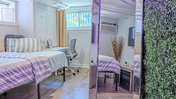 A bedroom with a large mirror, a bed with a plaid bedspread, a desk with a chair, and a green wall with foliage. - Cozy 1-bedroom apartment located in UNBEATABLE location Washington DC (Washington)