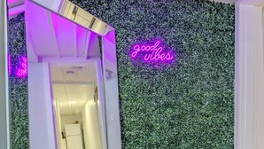 A hallway with a green wall, a neon sign reading "good vibes," and a mirrored wall reflecting the hallway. - Cozy 1-bedroom apartment located in UNBEATABLE location Washington DC (Washington)