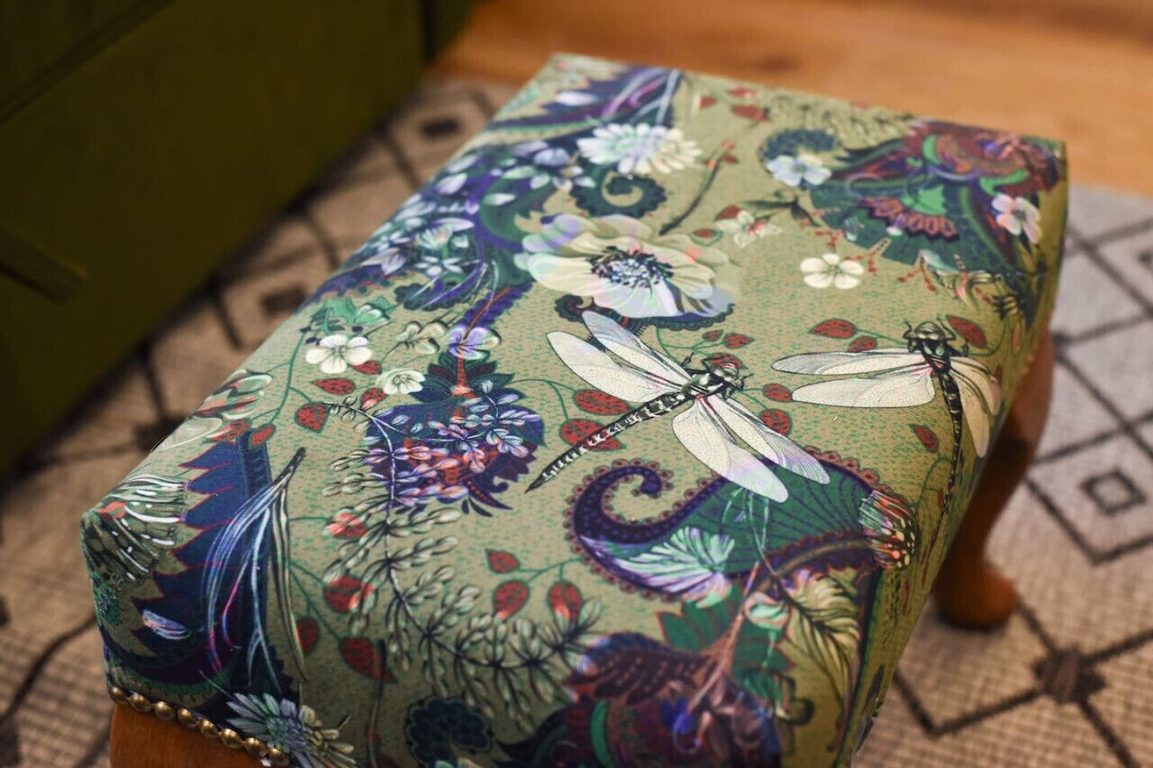 Un cojín estampado con motivos florales sobre una silla de madera.