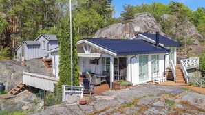 Un chalet rustique doté d’un porche couvert, d’une petite terrasse et d’un chemin de pierre menant à l’entrée.