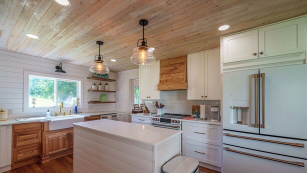 Una cocina moderna con armarios de madera, encimeras blancas y electrodomésticos de acero inoxidable.