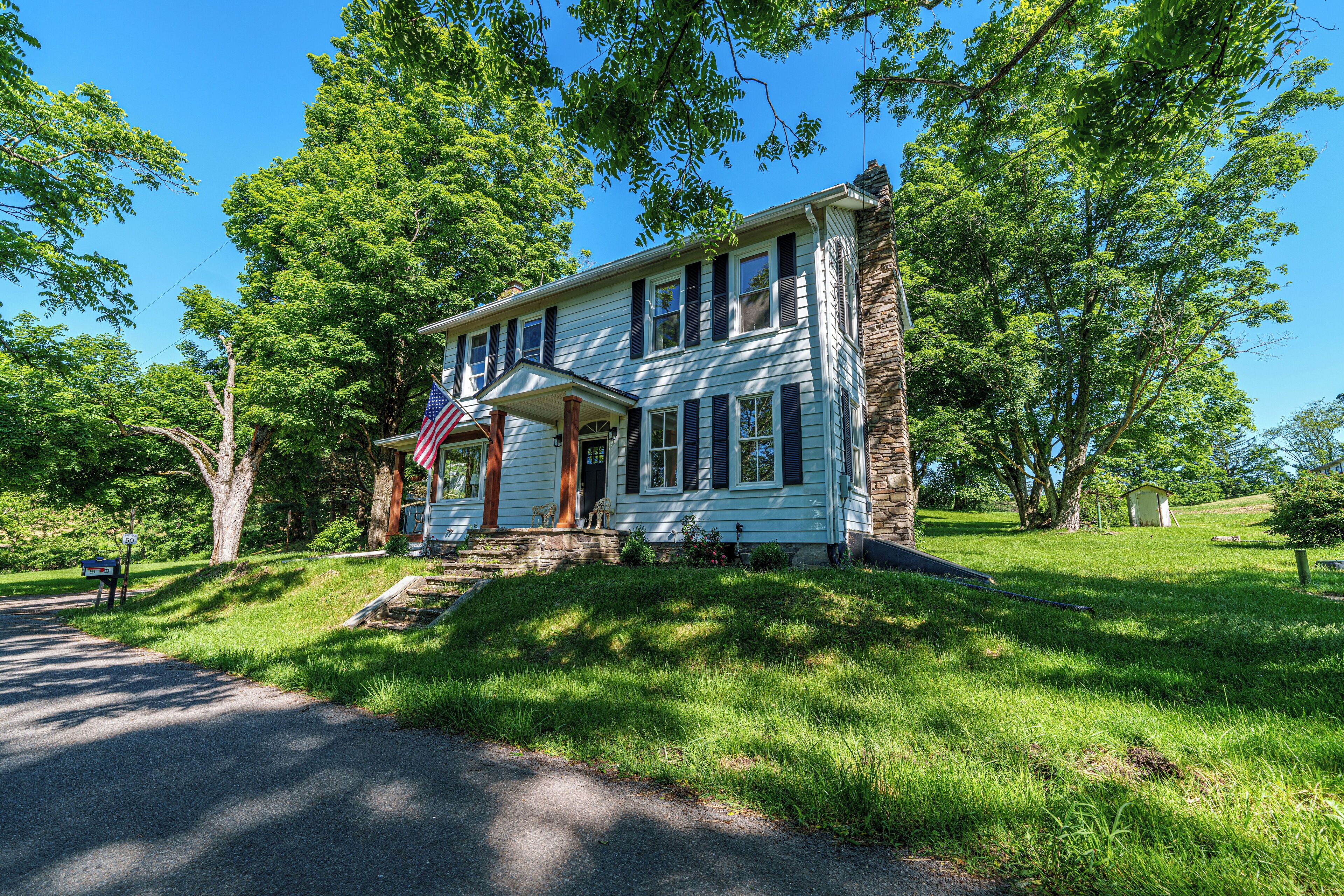 A two-story house with a front porch, a mailbox, and an American flag.