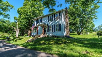 A two-story house with a front porch, a mailbox, and an American flag.