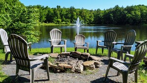 Un espacio de estar junto al lago con sillas Adirondack dispuestas alrededor de un brasero.