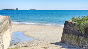 A beach with a stone wall and a small building in the distance. - Stunning home in La Pernelle with WiFi (La Pernelle)