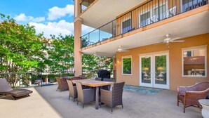 Une terrasse extérieure couverte, équipée d’une table et de chaises, d’un barbecue, et offrant une vue sur les bâtiments environnants.