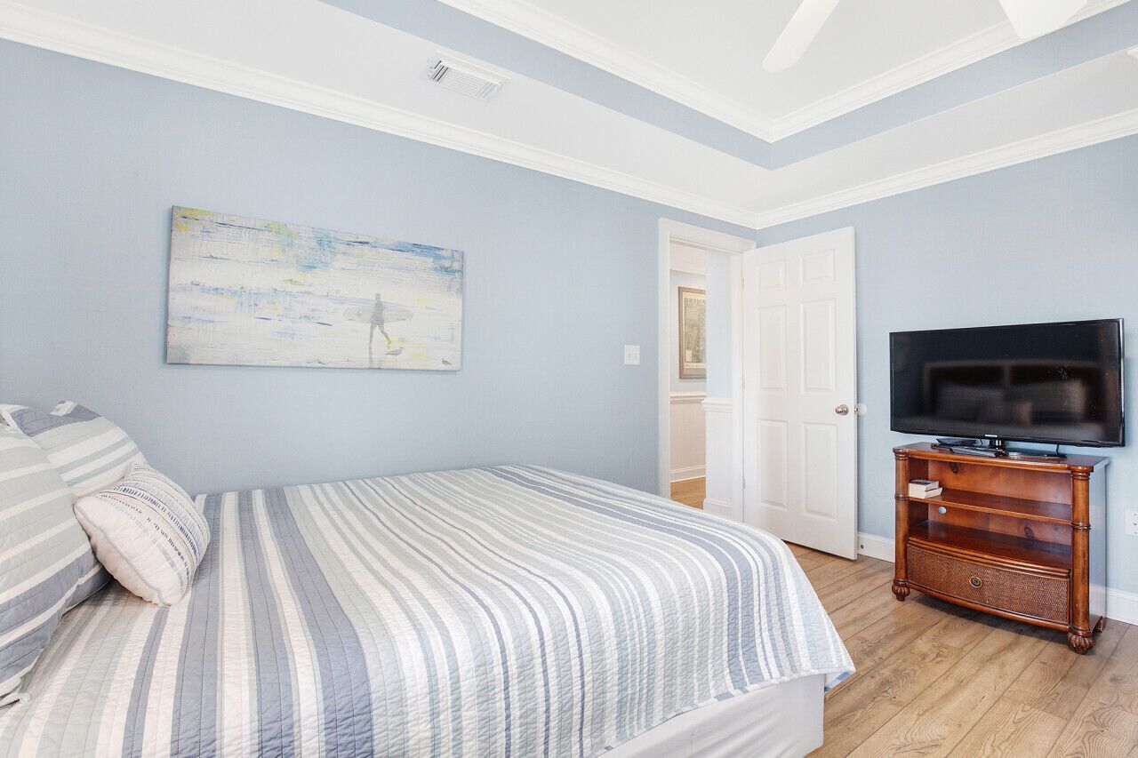 A bedroom with a bed, a television on a wooden stand, and a door.