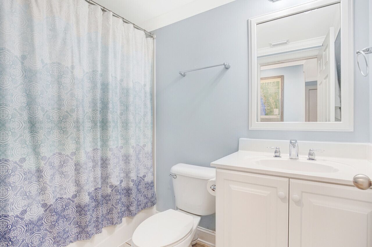 A bathroom with a toilet, a sink, and a mirror.