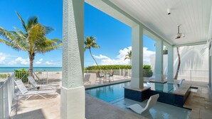 A pool area with lounge chairs, a small pool, and a view of the ocean. - Biltmore Beach House | Luxury 5-Br Beachfront Pool & Spa House | Sleeps 10 (Bonita Springs)