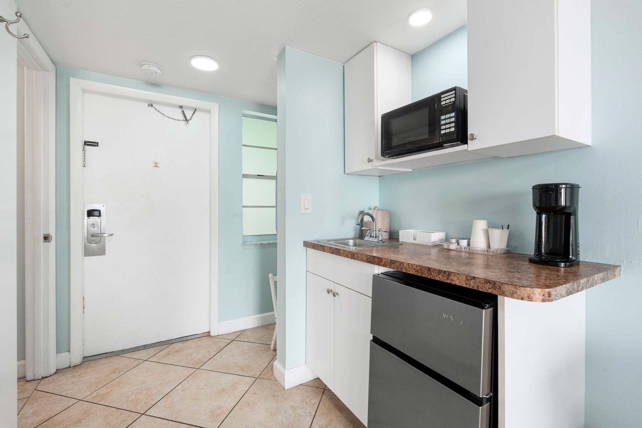 A compact kitchen with a microwave, coffee maker, and a refrigerator.