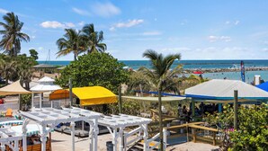 A beachside resort with outdoor seating areas, umbrellas, and a view of the ocean. - Ocean View Hotel Room with Balcony- 2 Full Beds #20 (Fort Pierce)