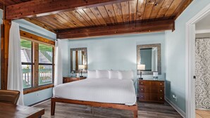 A bedroom with a wooden bed, a wooden desk, and a window with blinds. - Oceanfront Inn, Partial Ocean View, King Bed, #8 (Fort Pierce)