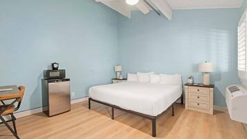 Une chambre à coucher comprenant un lit, des tables de chevet, un bureau et un réfrigérateur.