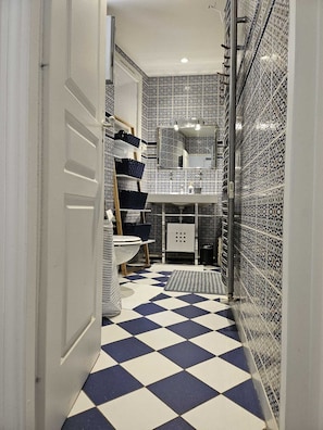 Bathroom features a checkered floor, geometric tile walls, and a white sink with mirror.